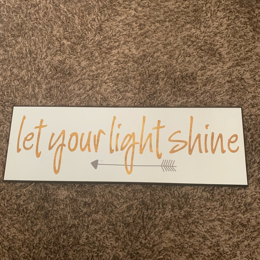 Wooden white wall plaque with gold lettering.